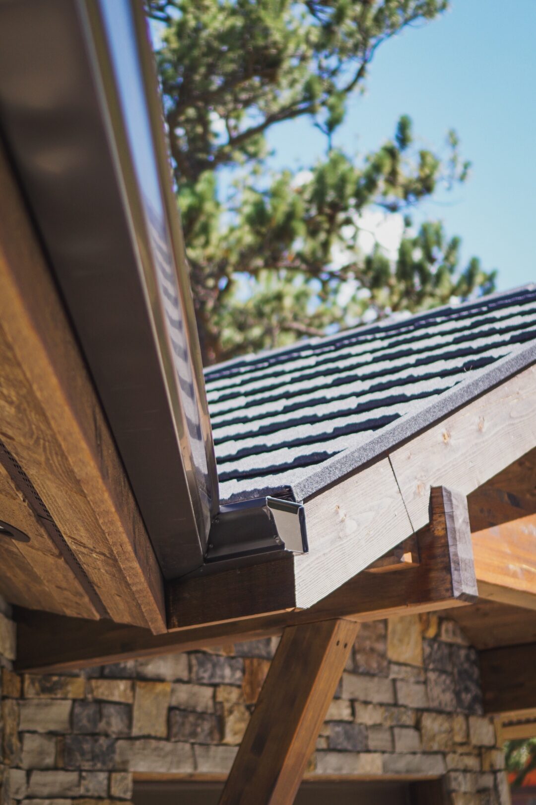Bronze seamless gutter end-cap installed at the rafter tail on a Colorado foothills mountain-modern home by Green Brothers Gutters.