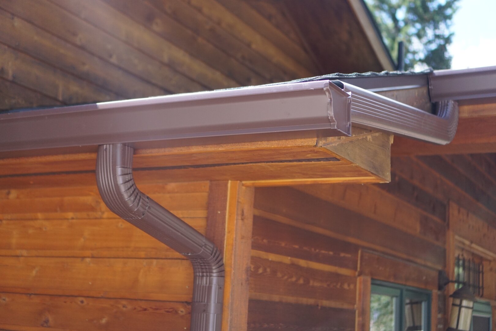 Bronze seamless gutter and matching downspout installed on a Colorado cedar cabin.